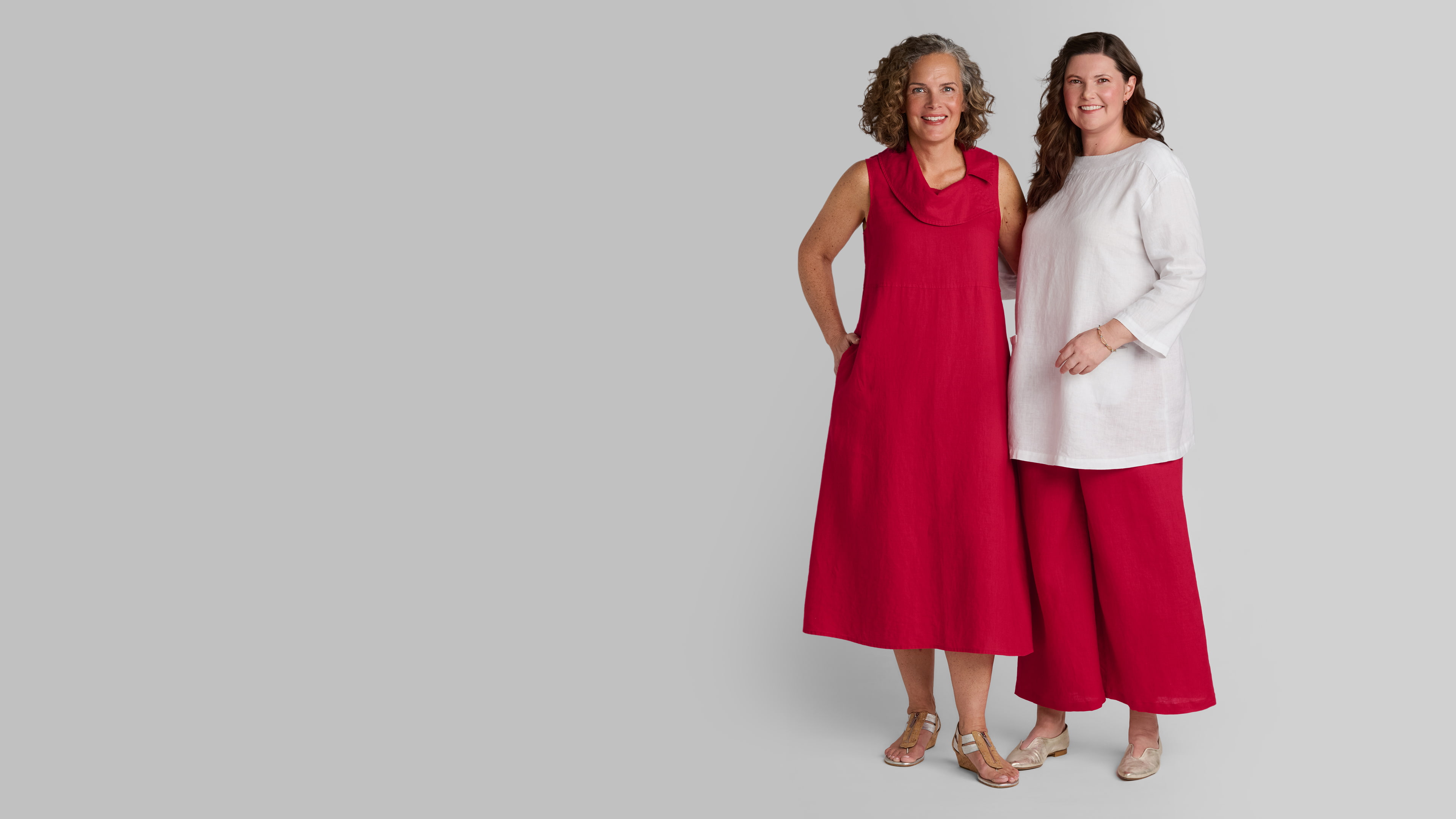 Woman in red linen dress and woman in white linen shirt with red linen wide leg pants